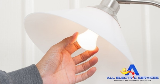 Photo of a lamp with a hand reaching for the light bulb